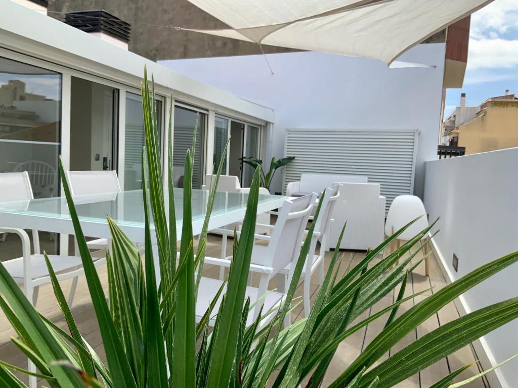 un patio al aire libre con sillas blancas y una planta en Dúplex Can Quim, Terrace Boutique Apartment, en L'Escala