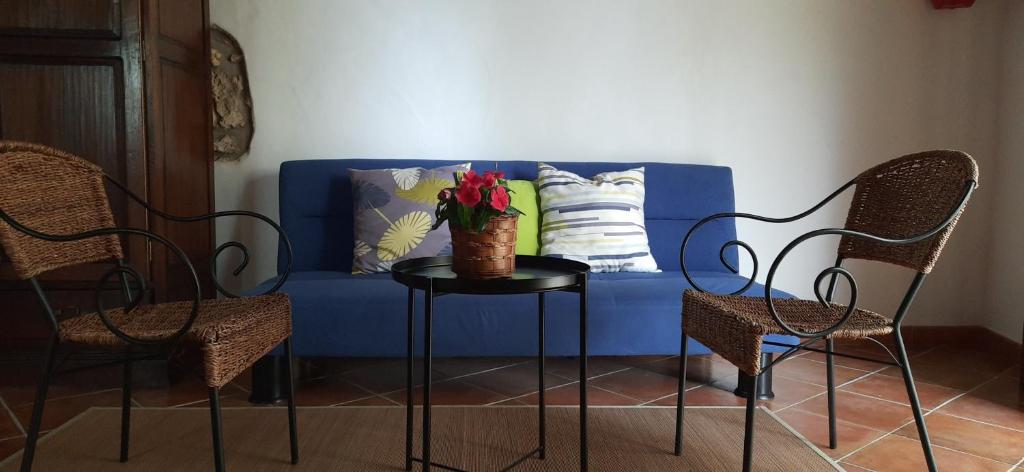a blue couch with a vase of flowers on a table at Casale Ginisara in Castellammare del Golfo
