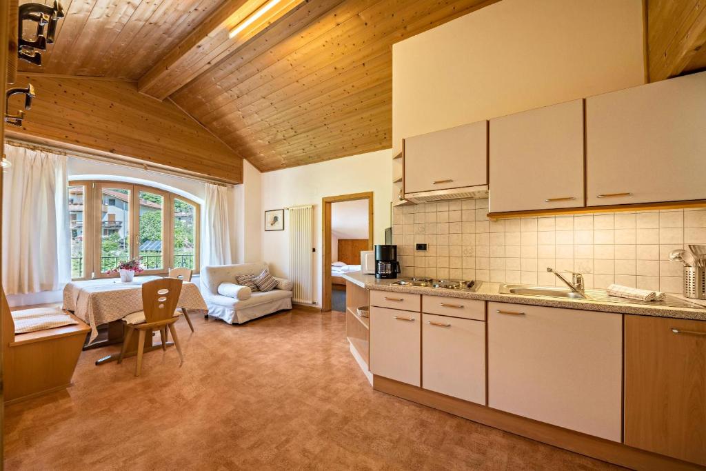 a kitchen with white cabinets and a living room at Baumgartnerhof Appartment Magnolie in Lagundo
