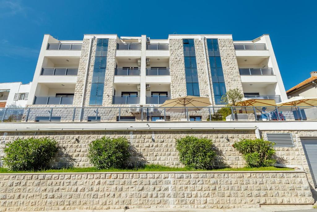 ein Apartmenthaus mit Ziegelwand und Regenschirm in der Unterkunft Doxa M Apartments in Herceg-Novi