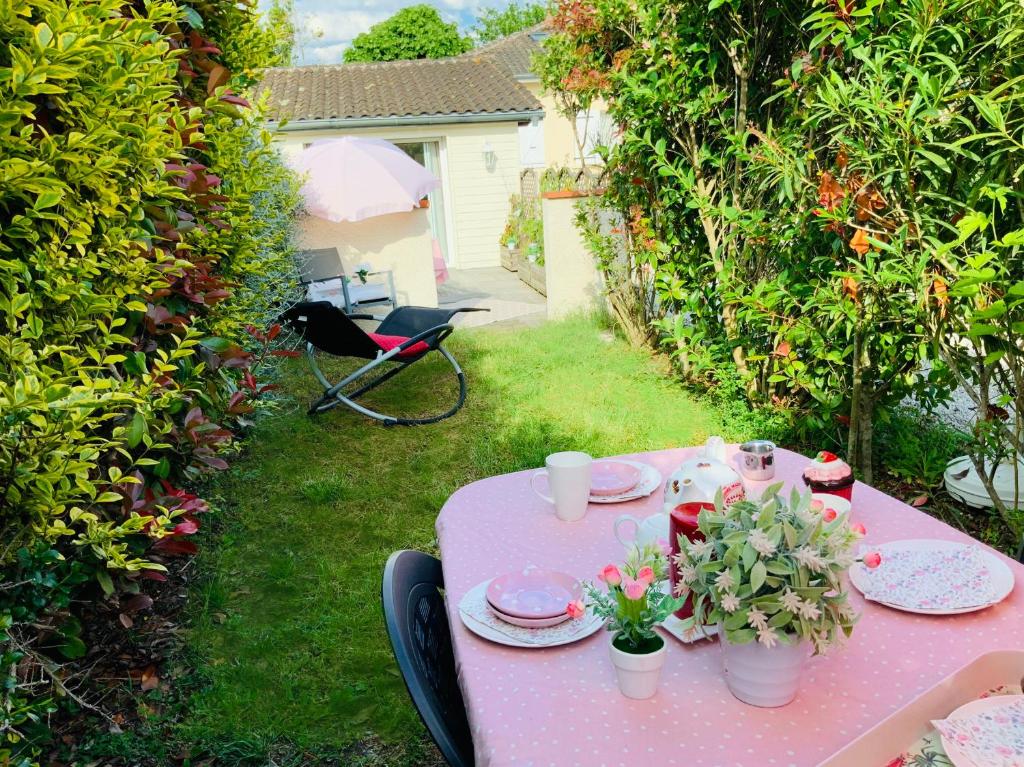 a pink table with plates and flowers on it at Cottage Blagnac in Beauzelle
