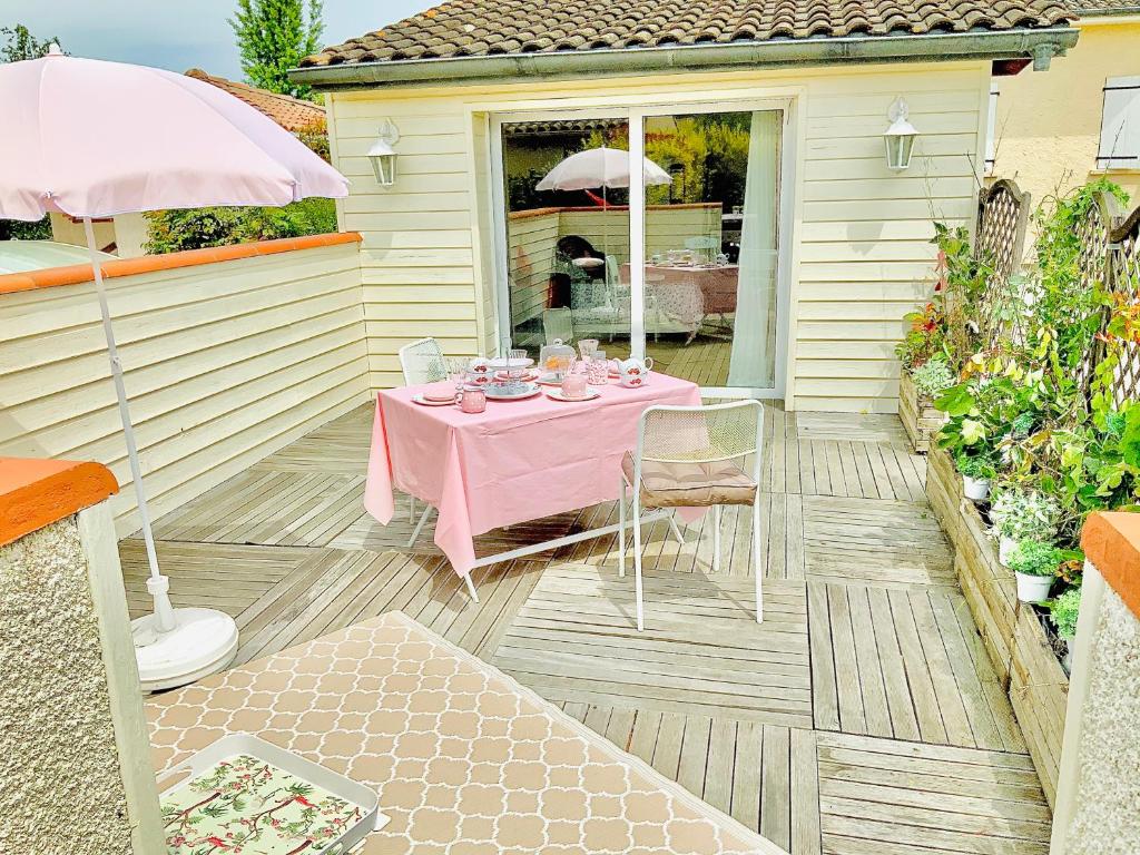 un patio con una mesa rosa y sillas. en Cottage Blagnac en Beauzelle
