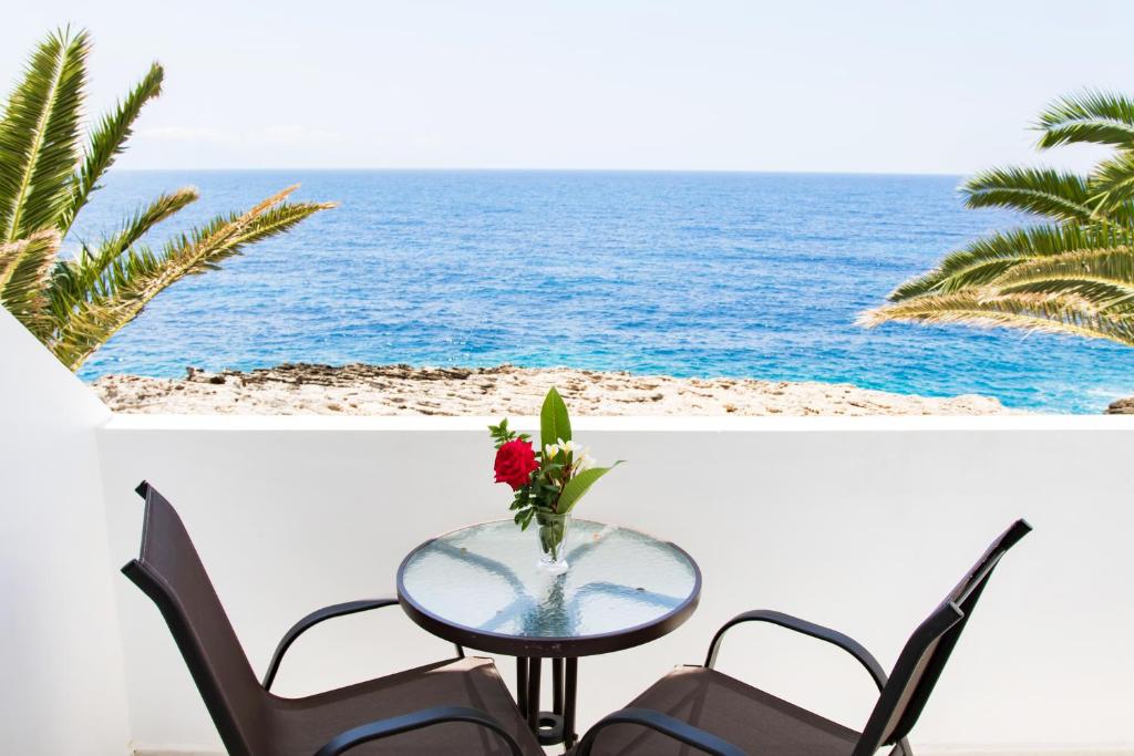 een tafel en stoelen met uitzicht op de oceaan bij Hotel Krinos in Karpathos