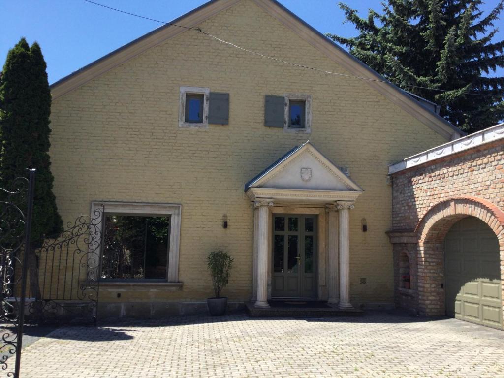 a yellow brick house with a gate and a driveway at Jókai Apartment in Sopron