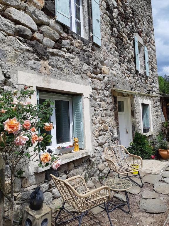 a stone building with two chairs and a window at L'EMBELLIE in Thueyts