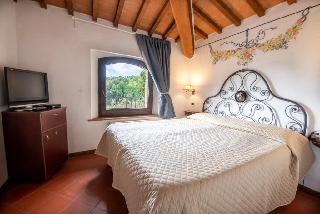 una camera con un letto bianco e una finestra di Hotel Vecchia Oliviera a Montalcino