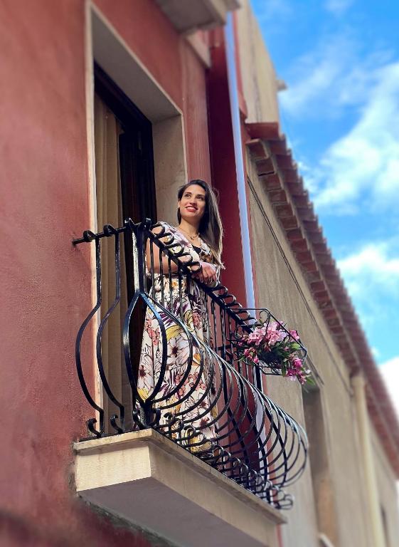 a woman looking out of a balcony with flowers at Domus Cuseni in Taormina