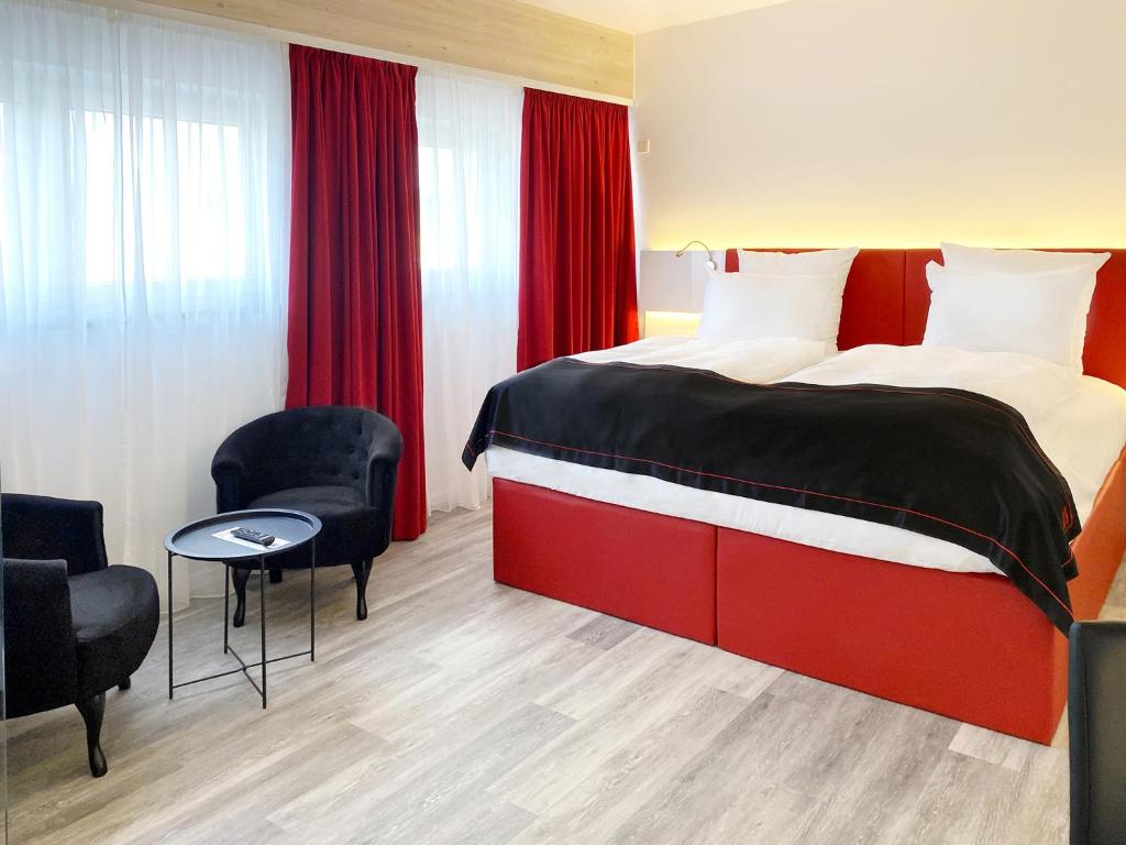 a hotel room with a bed and two chairs at DORMERO Hotel Deggendorf in Deggendorf