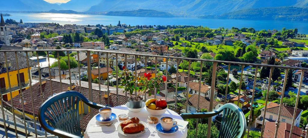 a table with food on a balcony with a view of a city at Robertalagocomo in Gravedona