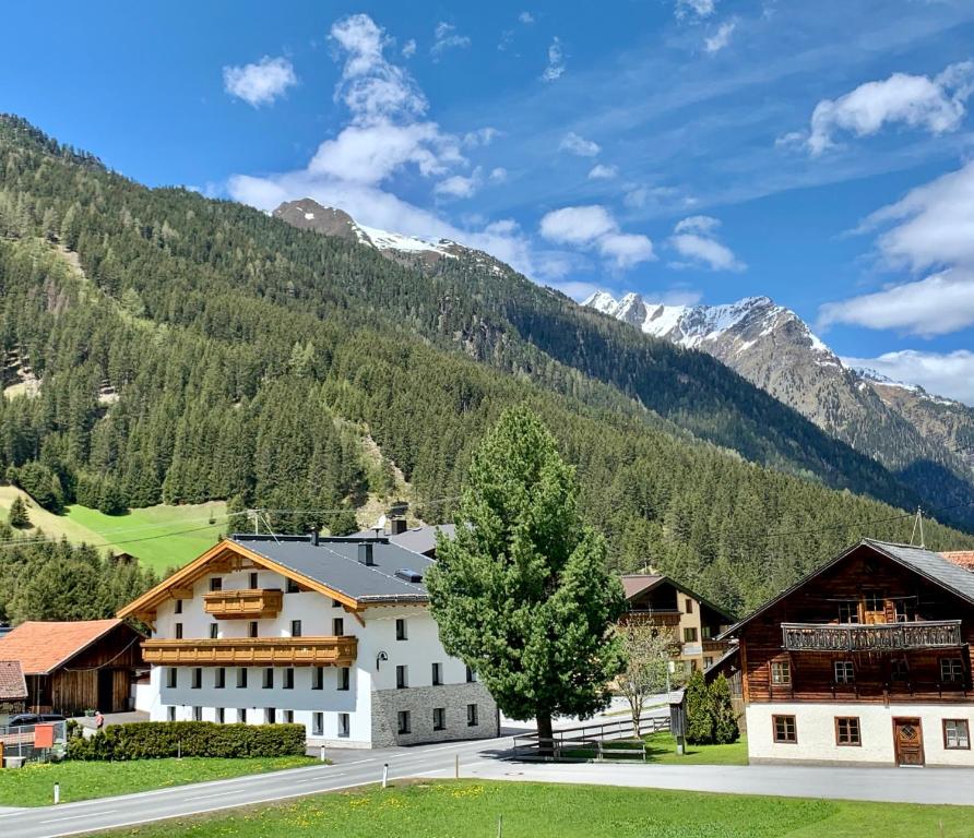 a large white building with mountains in the background at APART Kirschner in Sankt Leonhard im Pitztal