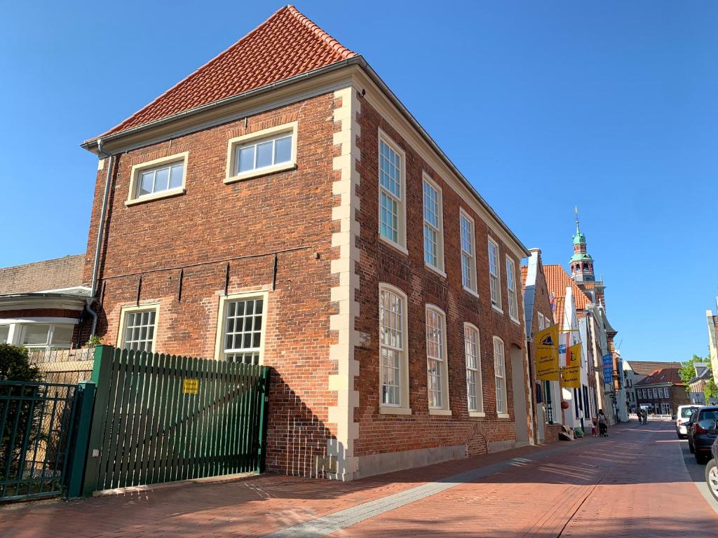 un edificio de ladrillo rojo con una valla negra en una calle en Haus Äskulap - Altstadt, Hafen, Gallimarkt en Leer