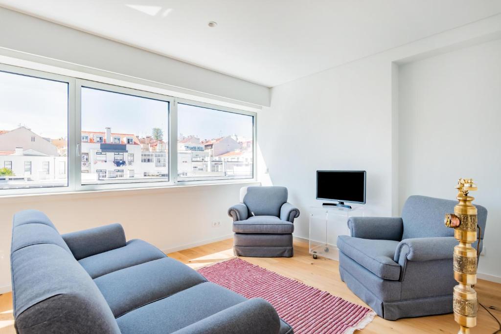 uma sala de estar com um sofá e duas cadeiras e uma televisão em Estrela Modern Flat @ Infante Santo em Lisboa