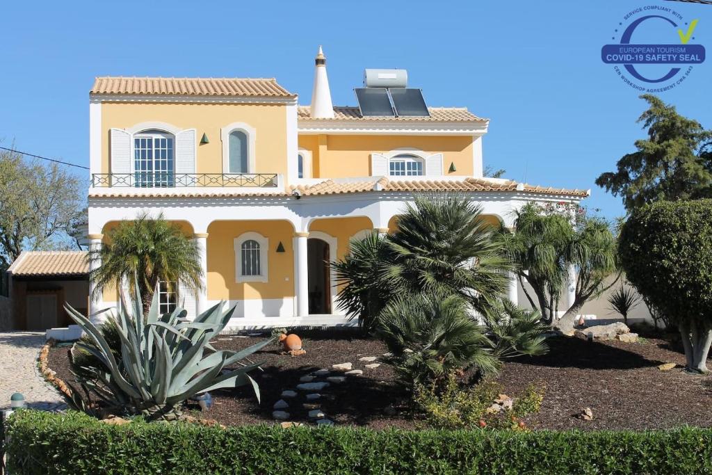 uma grande casa amarela com palmeiras em frente em Villa Coelho by Trip2Portugal em Olhão