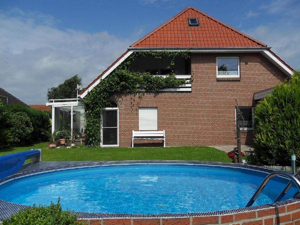 a house with a large swimming pool in front of it at Ferienwohnnung Kathrin in Wremen