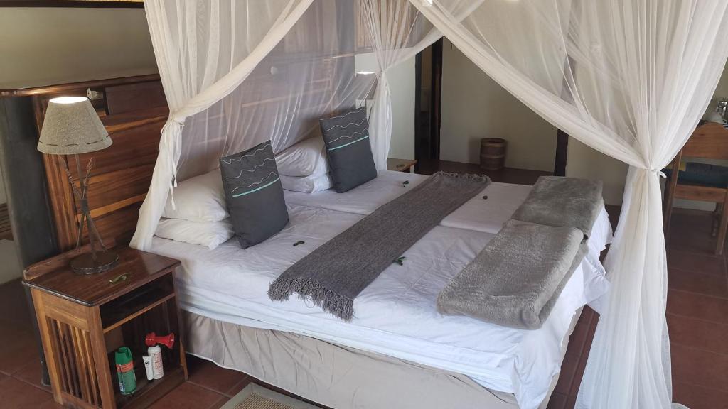 a bedroom with a canopy bed with white sheets and pillows at Lianshulu Lodge in Kongola