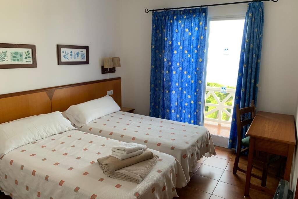 a bedroom with two beds and a window at Apartamento en Playa Santo Tomas 1-5 in Es Migjorn Gran