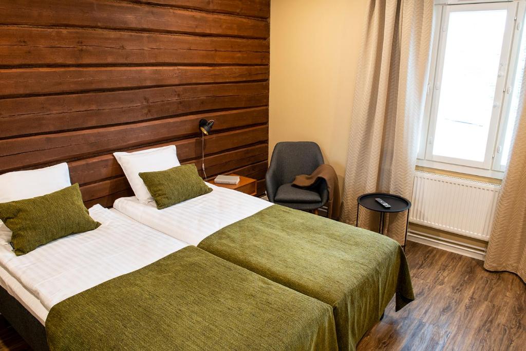 um quarto com uma cama, uma cadeira e uma janela em Kuortane Kuharanta em Mäyry