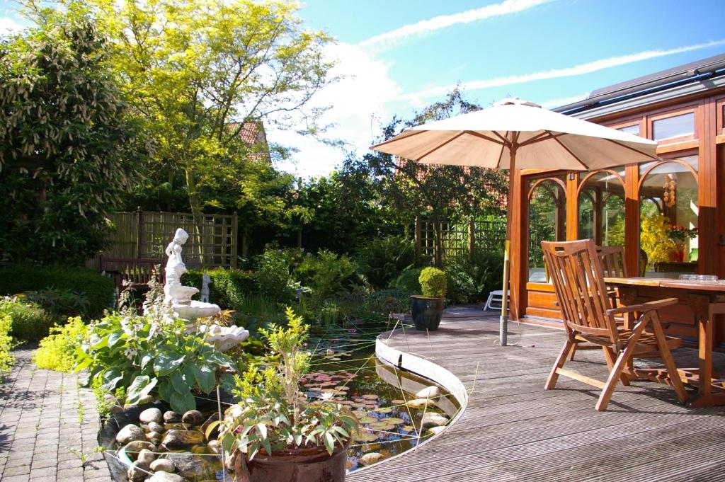 eine Terrasse mit einem Sonnenschirm, einem Tisch und Stühlen in der Unterkunft B&B VILLA MONIQUE in Koksijde