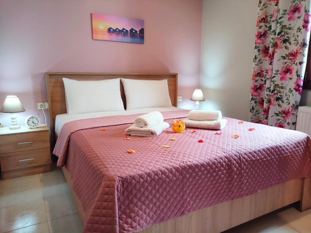 a bedroom with a pink bed with towels on it at Philoxenia Guest House in Makrirrákhi