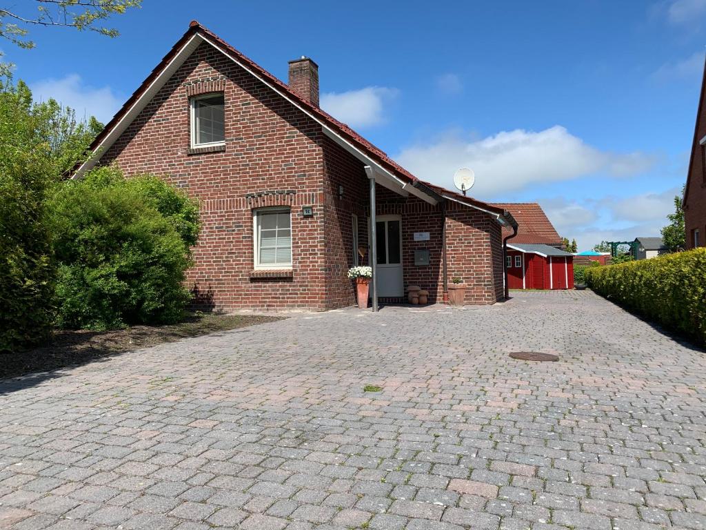 une maison en briques avec une allée en briques devant elle dans l'établissement Neuhaus Deichperle, à Krummhörn