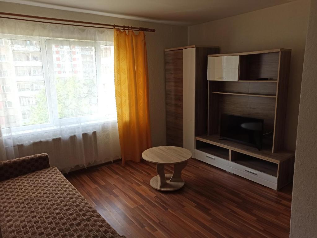 Una sala de estar con un sofá, una mesa y un televisor. en Inzenieru 75 Apartments, en Ventspils
