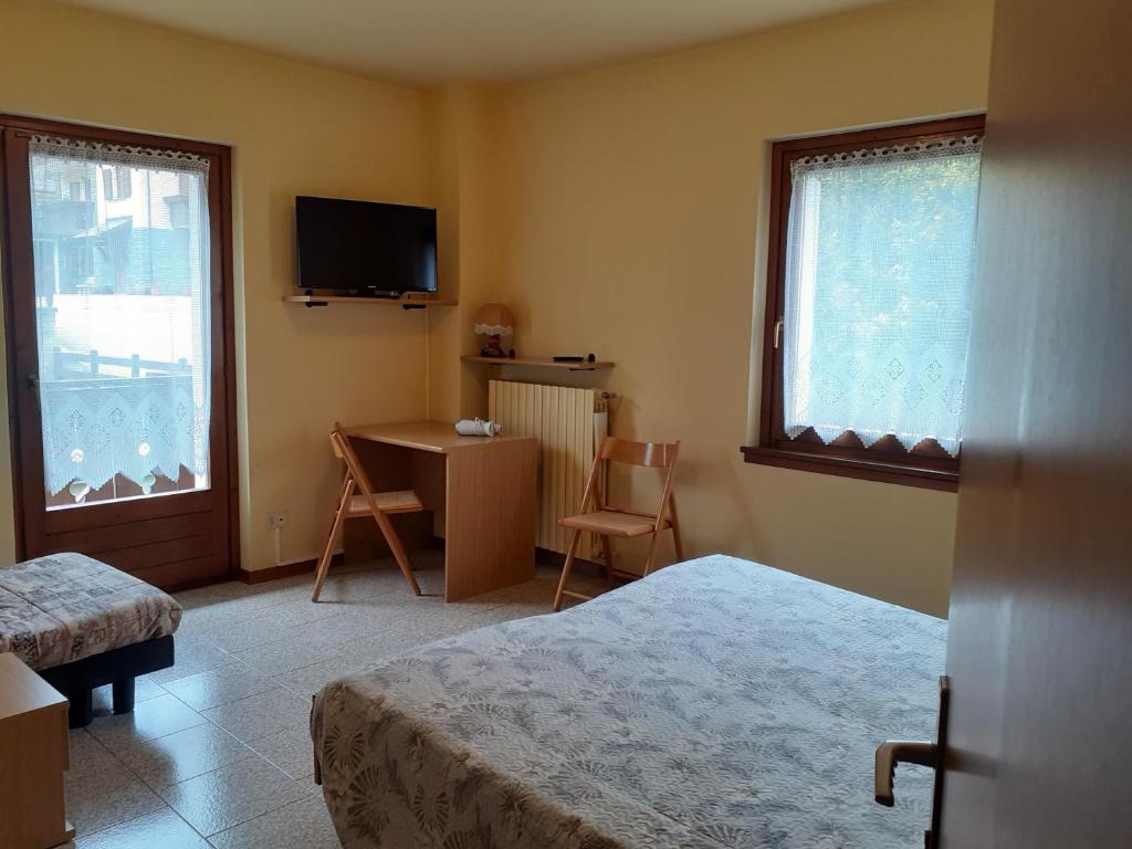 a bedroom with a bed and a desk and a television at Residence Iris BeB in Valdisotto