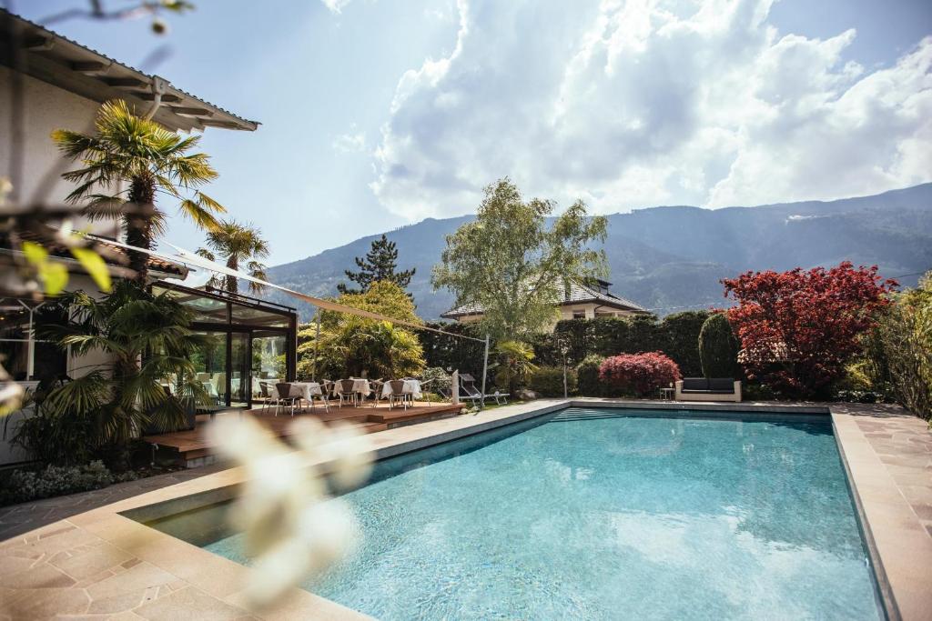 a swimming pool in a house with mountains in the background at Hotel Rablanderhof in Rablà
