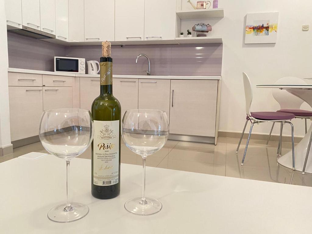a bottle of wine and two wine glasses on a table at Apartman Krešo in Makarska
