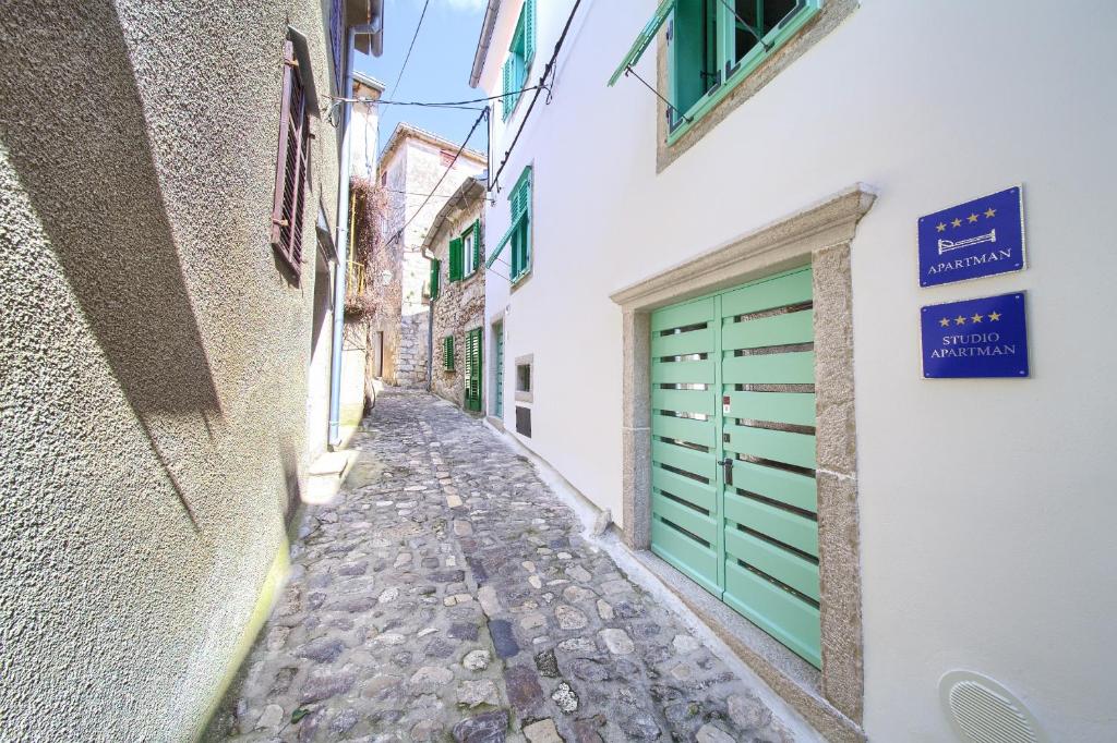 an alley with a green garage door on a building at Apartments Bastinica in Krk