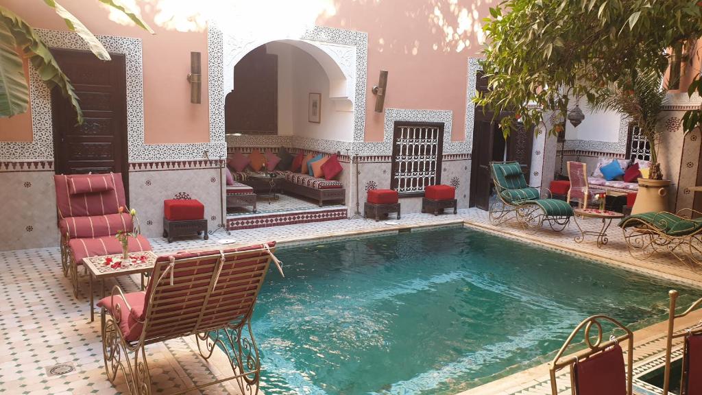 a swimming pool in a house with chairs and a couch at Riad Barroko in Marrakesh