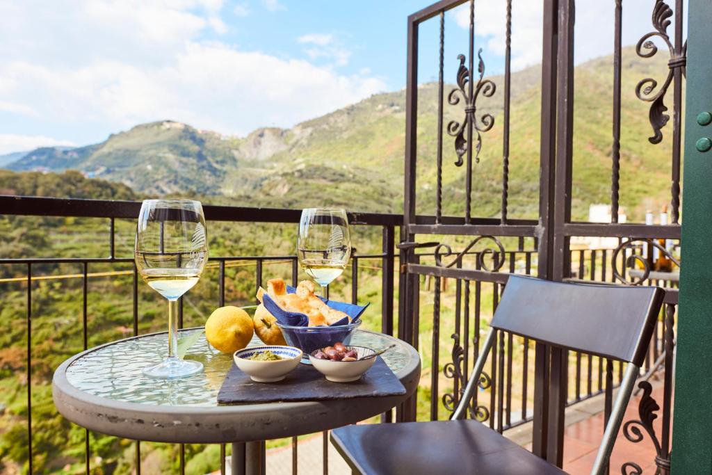 a table with two glasses of wine and fruit on a balcony at il Magàn - Cinque Terre in Corniglia