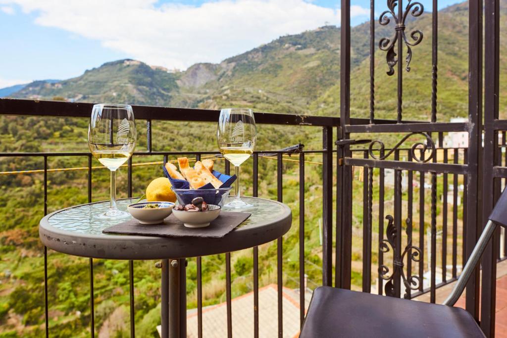 a table with two glasses of wine and a bowl of fruit at il Magàn - Cinque Terre in Corniglia