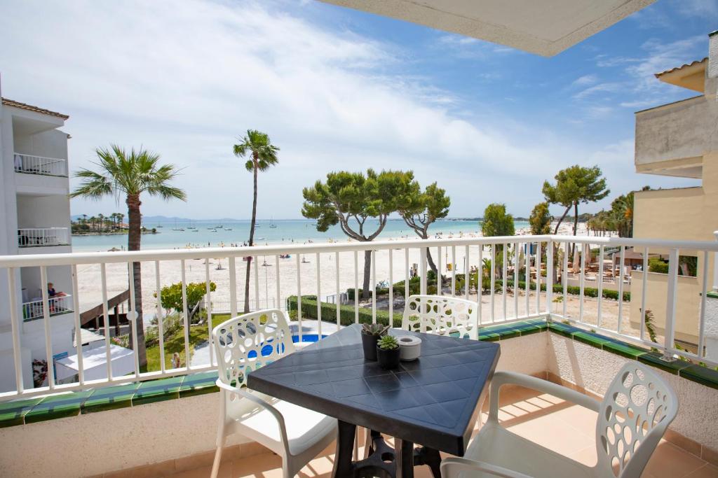 a balcony with a table and chairs and the ocean at Sand Beach Apartments in Port d'Alcudia