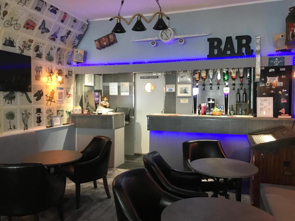 a bar with black chairs and tables and a counter at Brene Hotel in Blackpool