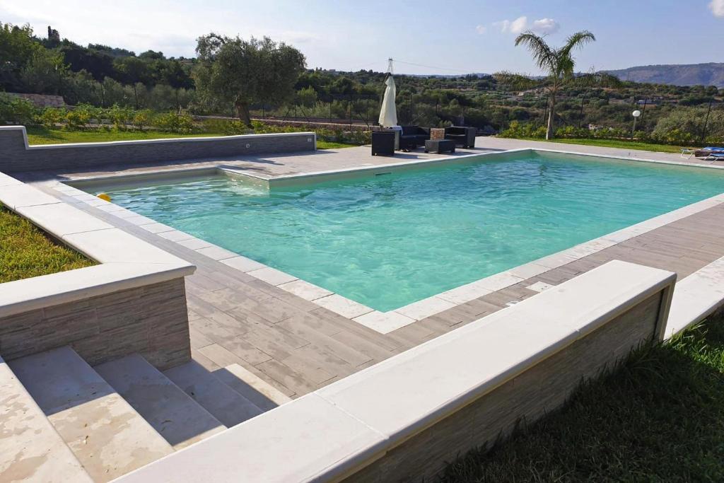 een zwembad in een tuin met een patio bij Holiday Home Solarino - ISI02101h-F in Solarino