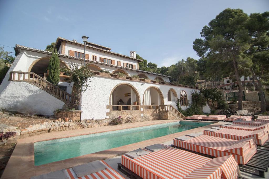 uma casa com uma piscina com espreguiçadeiras em Villa Dora (Only adults) em Xàbia
