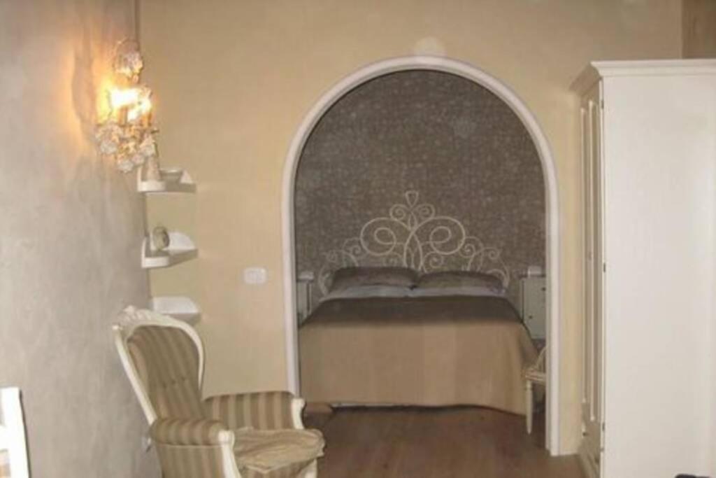 ein Schlafzimmer mit einem Bett in einem Torbogen mit einem Stuhl in der Unterkunft The Luxury Madonnina Suite in Vernazza