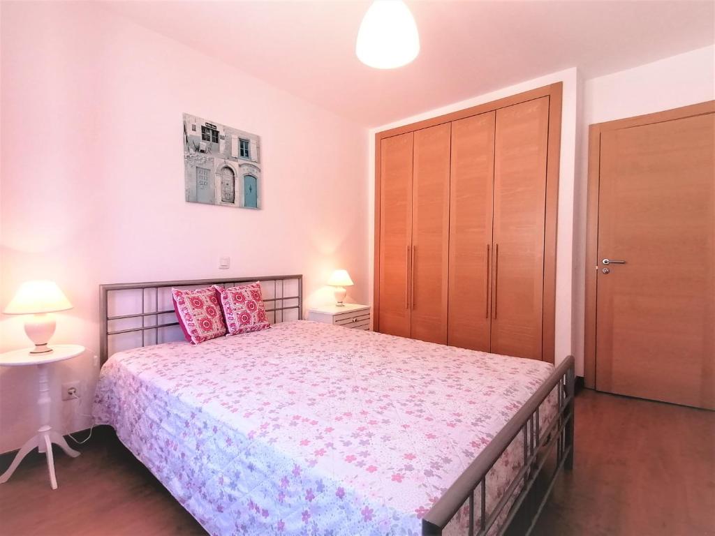 um quarto com uma cama grande e uma porta de madeira em Encosta da Marina Beach Apartment em Portimão