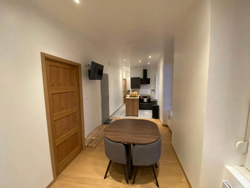 uma sala de jantar com mesa e cadeiras e uma cozinha em Appartement cosy au cœur des Vosges em Épinal