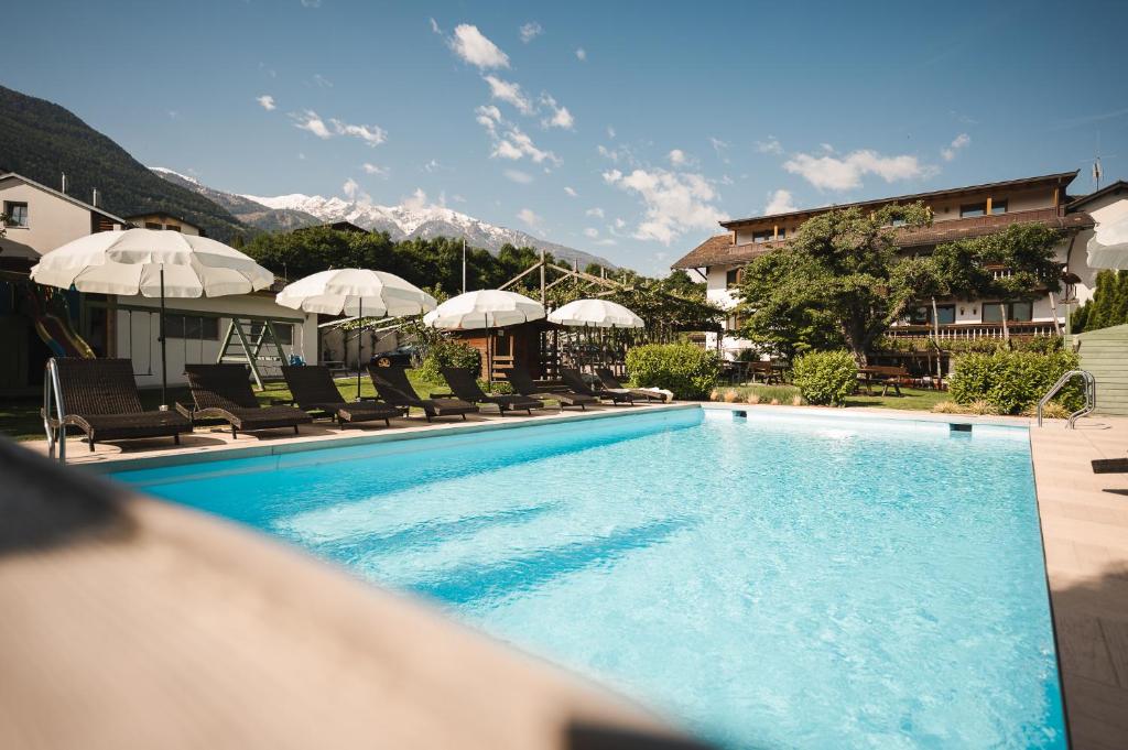 a large swimming pool with chairs and umbrellas at Hotel Bauhof in Castelbello-ciardes