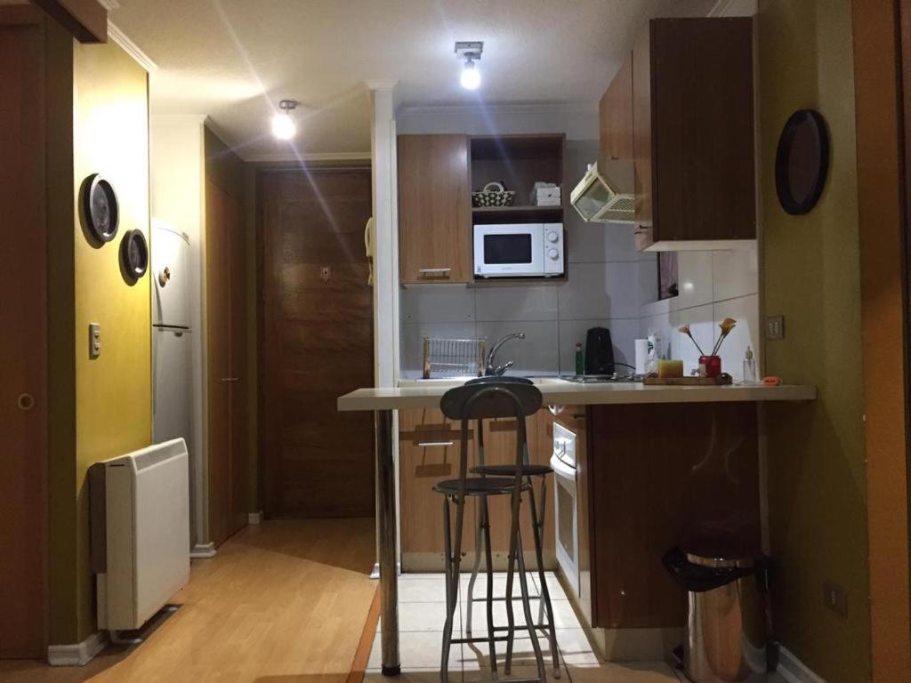 a kitchen with a counter and two bar stools at Apartamento Metro Santa Lucia, Santiago Centro in Santiago