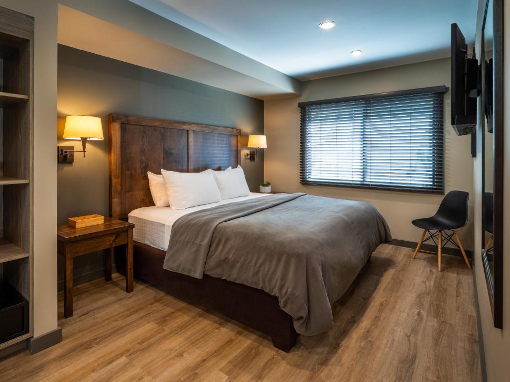 a bedroom with a bed and a window and a chair at Buffalo Mountain Lodge in Banff