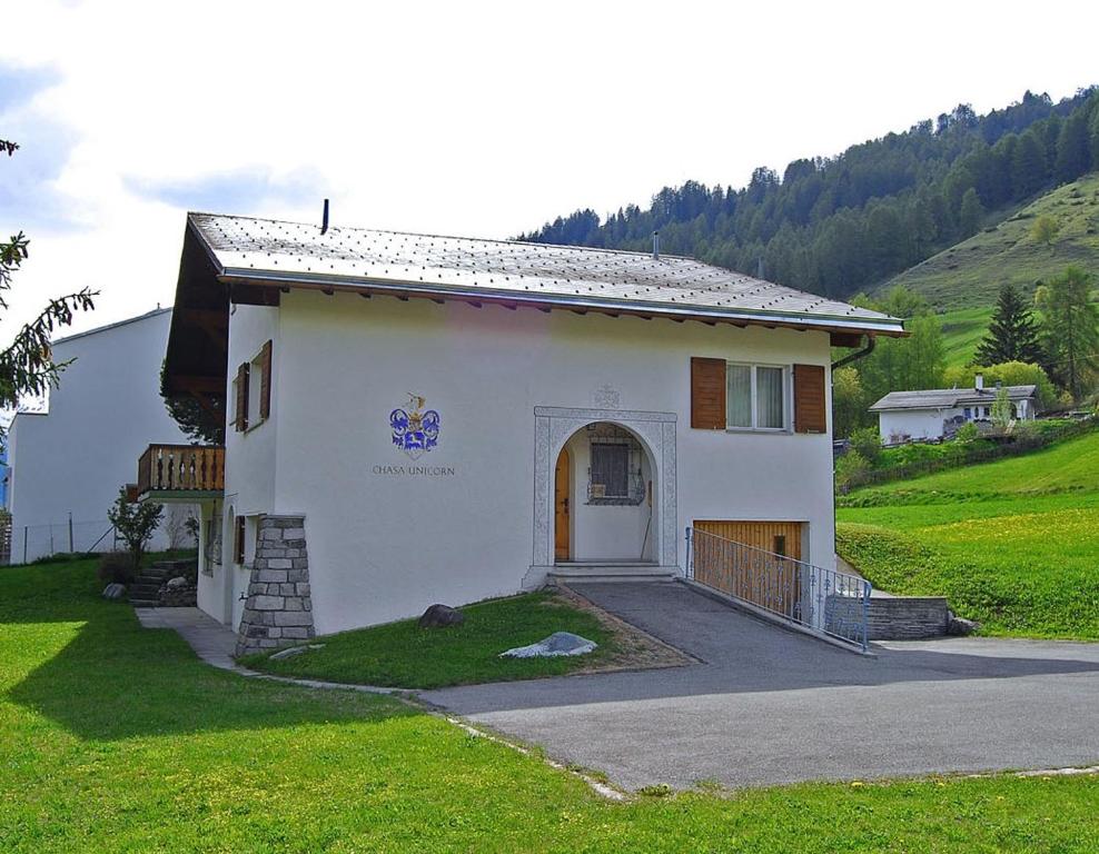 una pequeña casa blanca en un campo con una colina en Feriendomizil zum Schalten und Walten, en Scuol