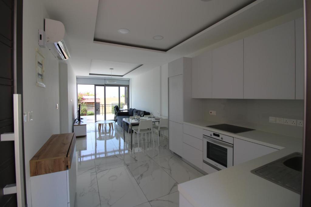 a kitchen with white cabinets and a dining room at 42 Beach Coast Apartment in Polis Chrysochous