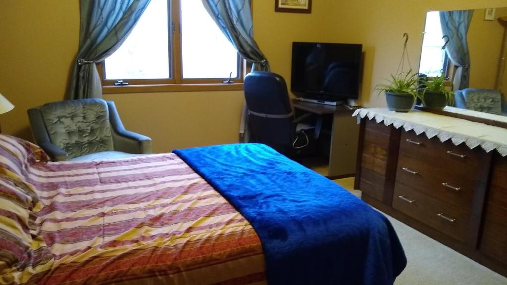 um quarto com uma cama, uma secretária e uma televisão em Moreland Air Venture Rooms em Oshkosh