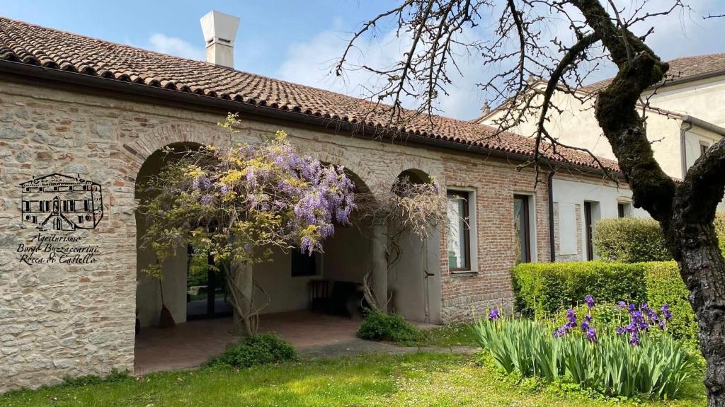 una entrada a una casa de ladrillo con flores púrpuras en Agriturismo Borgo Buzzaccarini Rocca di Castello en Monselice