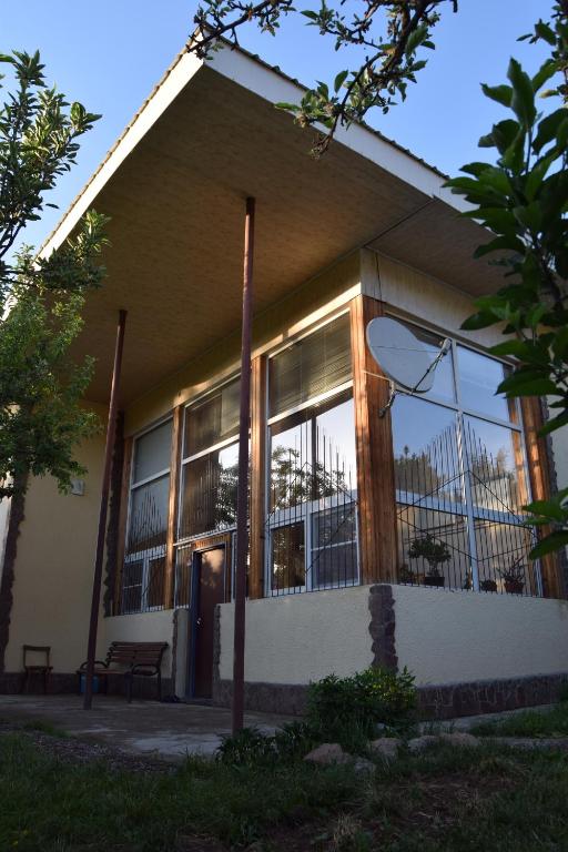 ein Gebäude mit großen Fenstern und einer Bank davor in der Unterkunft Гостевой дом Chimgan Apple Garden in Chimgan