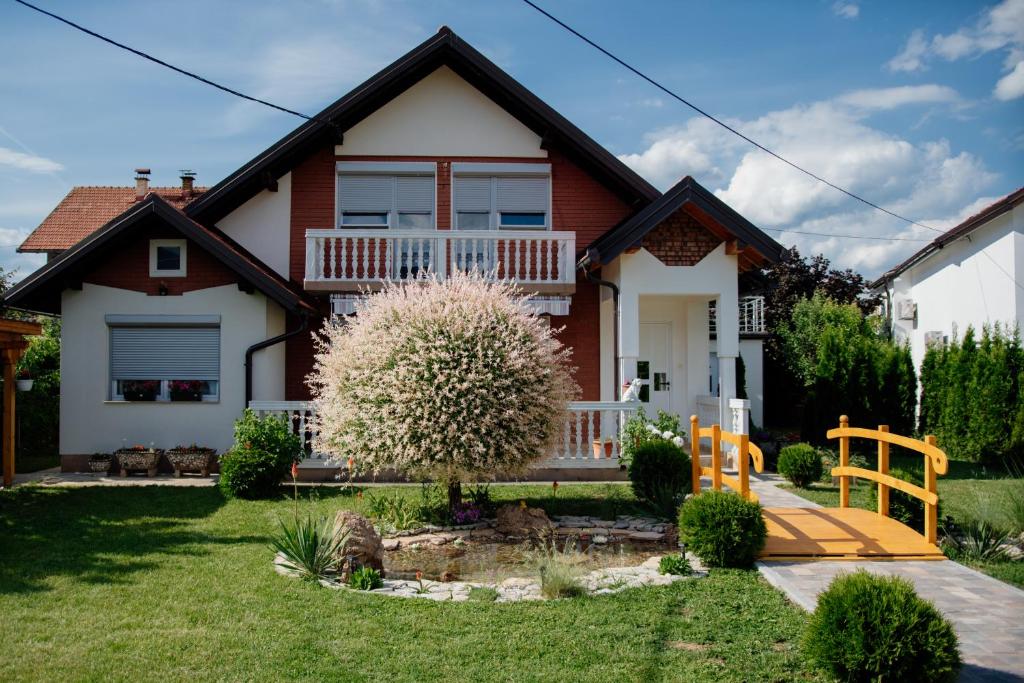 a house with a flowering tree in the yard at Villa Medina in Sarajevo