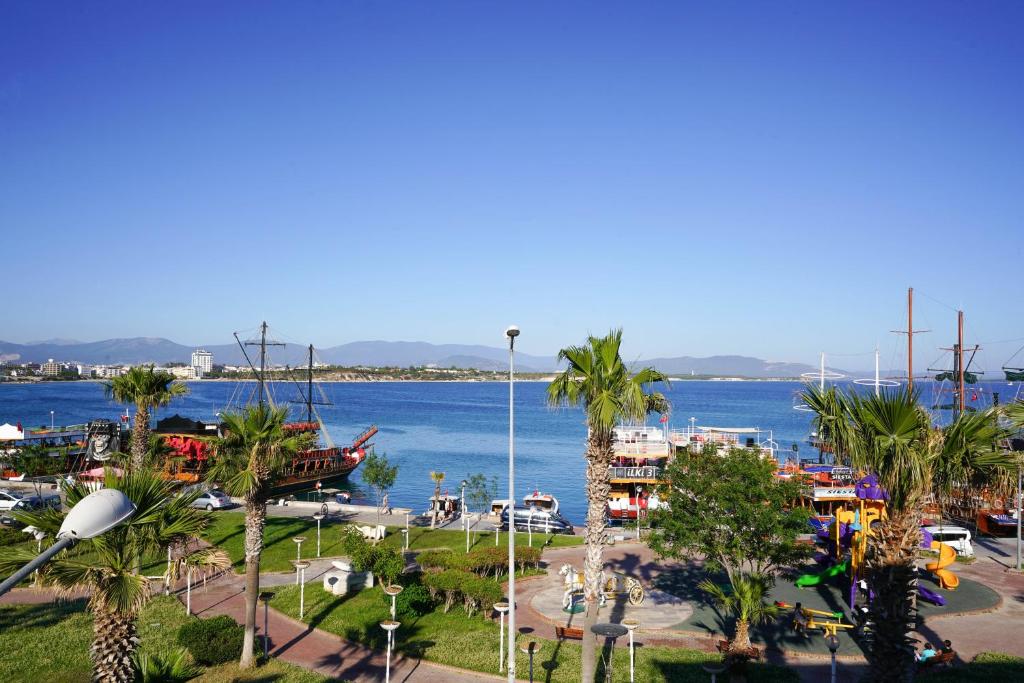 a harbor with palm trees and a body of water at Arden Hotel in Didim