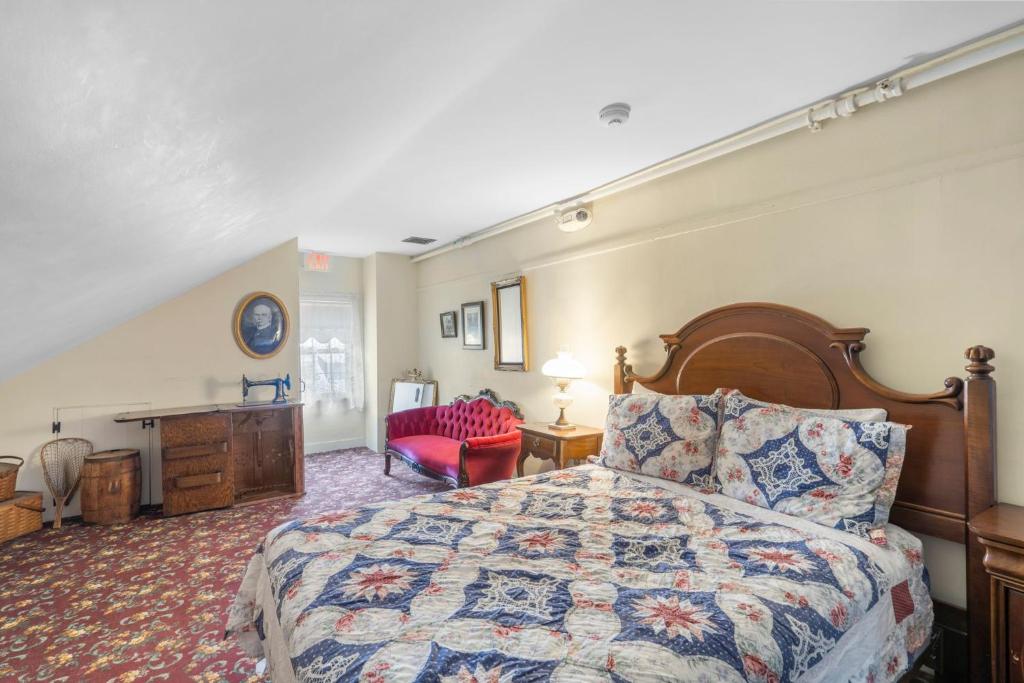 um quarto com uma cama grande e uma cadeira vermelha em Lizzie Borden House em Fall River